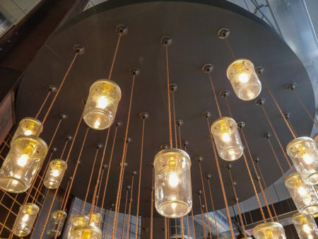 A collection of beautifully crafted mason jar lights is elegantly hanging down from the ceiling,...