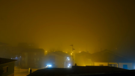 A city at night wrapped in a thick layer of fog, illuminated by countless lights that create a mesmerizing atmosphereの写真素材