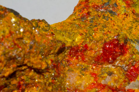 A close-up macro photograph of a mineral surface with a mix of yellow and red hues, showing intricate textures and patterns.の写真素材