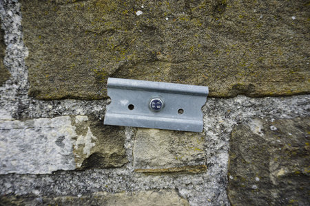 A close-up shot of a metal bracket attached to a textured stone wall.