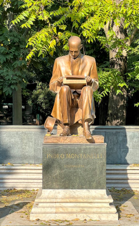 A full shot of the statue of Indro Montanelli, an Italian journalist and writer, seated on a bench in a park, holding a book.の写真素材