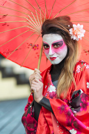 A woman elegantly dressed in a vibrant red kimono is gracefully holding a matching red umbrella, creating a beautiful sceneの写真素材