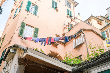 Colorful laundry hanging between traditional buildings in a narrow alleyway in Genoa, Italy, capturing a slice of daily life and the vibrant character of the city.の写真素材