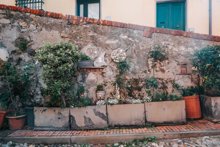 A rustic stone wall adorned with potted plants, decorative plates, and greenery, creating a charming outdoor space.の写真素材