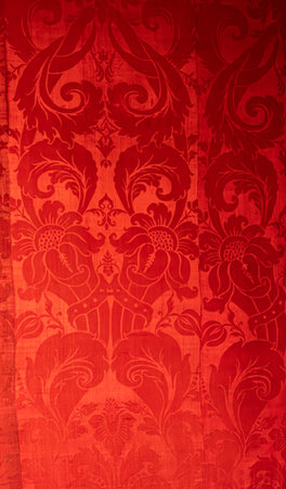 A close-up shot of an antique wall covering made of fabric with a repeating floral pattern, showcasing vintage design.の写真素材