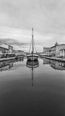 A beautiful antique boat docked in the picturesque canal harbor of Cesenatico, Italy.の写真素材