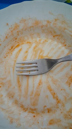 An empty plate with a fork, showing the remnants of a meal.の写真素材