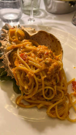Plate of spaghetti with spider crab sauce, served artistically inside a spider crab shell. Part of the crab's body is also visible. High quality photoの写真素材