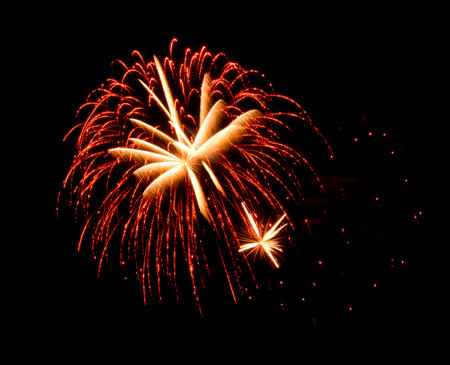 Two golden firework light streaks crossing each other against a dark background, captured during an explosion. High quality photoの写真素材