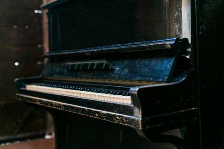 A vintage, upright piano with a distressed, black finish, showcasing its age and character, set...