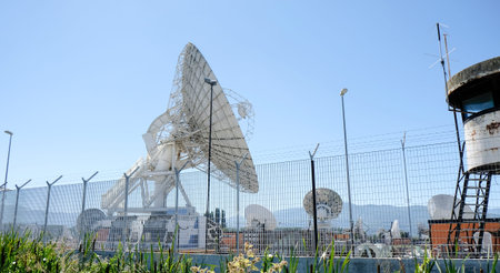 A wide shot of multiple large white satellite dishes at the Telespazio Fucino Space Centre, set...