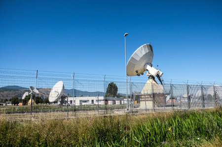 A wide shot of multiple large white satellite dishes at the Telespazio Fucino Space Centre, set...