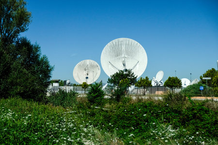 A wide shot of multiple large white satellite dishes at the Telespazio Fucino Space Centre, set...