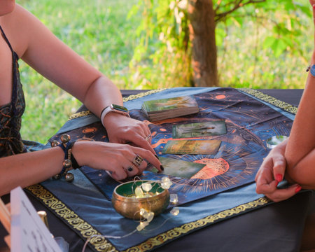 A woman is sitting comfortably at a table with her hands resting thoughtfully on a tarot card, reflecting on its meaning and significanceの写真素材
