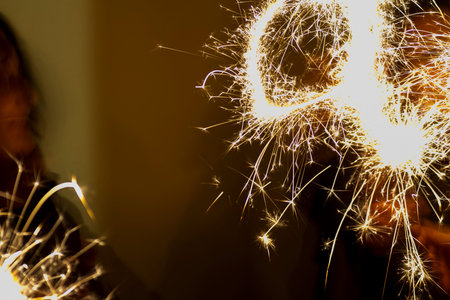 A joyful individual is happily holding colorful sparklers right in front of their smiling face, creating a vibrant atmosphereの写真素材