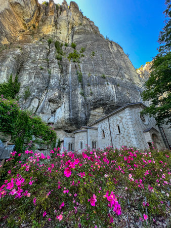 The imposing, sheer rock face of Pietra di Bismantova towers above, viewed from its base, surrounded...