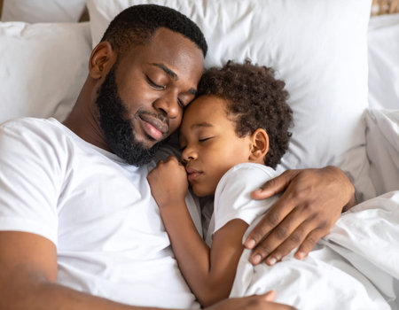 A dad is peacefully laying on a bed with a baby, creating a serene atmosphere filled with love and warmth as they both rest togetherの素材