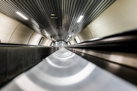 A low-angle, dynamic perspective view down a very long escalator in a subway station, emphasizing depth and modern design. High quality photoの写真素材