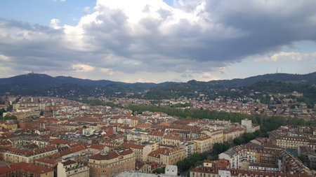 A panoramic view of the Turin skyline, with rays of sunlight breaking through the clouds and the...