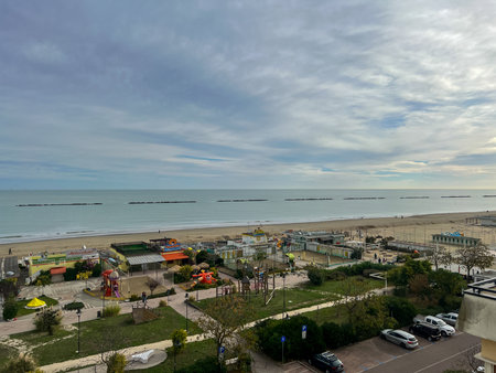 An elevated panoramic view of Cesenatico's sandy beach, calm Adriatic Sea, and a vibrant seaside park on a cloudy autumn or spring day. . High quality photoの写真素材