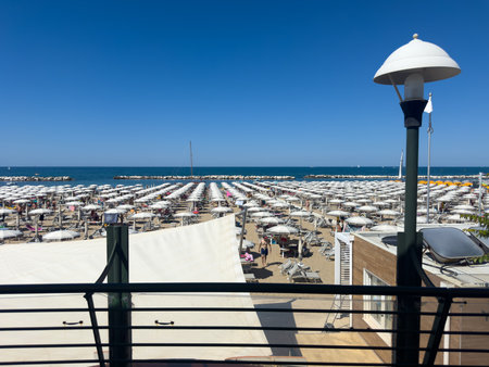 An elevated, wide view of a very crowded, commercially organized beach, completely covered by densely packed rows of white umbrellas and sunbeds under a bright blue sky. High quality photoの写真素材