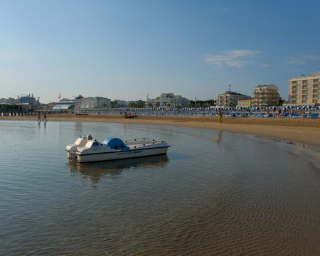 A small white boat resting on the sandy beach with calm Adriatic waters and distant buildings under a clear summer sky. High quality photoの写真素材