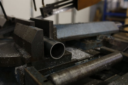 Metal Pipe Clamped In Industrial Vise, CloseUp Showing Freshly Cut Tube End Surrounded By Metal...