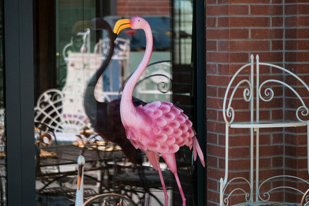 Pink Flamingo Ornament Behind Glass Window, Vintage Storefront Display With Brick Facade, Reflected Urbanの写真素材