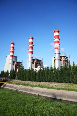 Power plant chimneys producing white smoke against a blue skyの写真素材