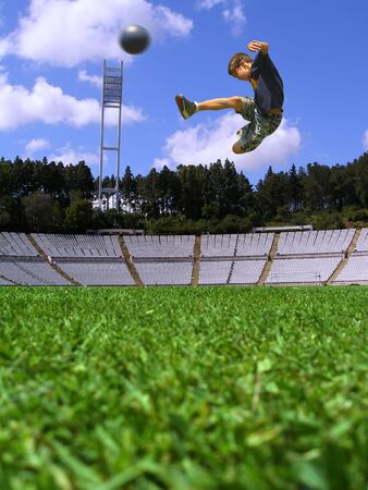 Boy playing soccer in a green grass fieldの写真素材