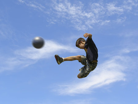 Boy playing soccer against the sky