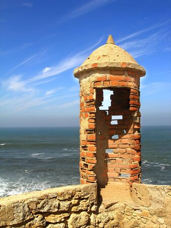 ancient watch tower with the blue ocean and sky in the backgroundの写真素材