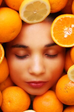 Beautiful woman face framed with oranges and lemonsの写真素材