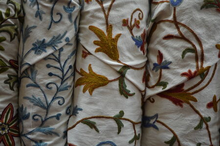Stacks of cloth with colorful embroideries in floral patternsの写真素材