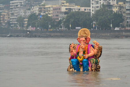 Mumbai, India - September 2013 - Hindu God Ganesha immersing into the ocean with background of cityのeditorial素材