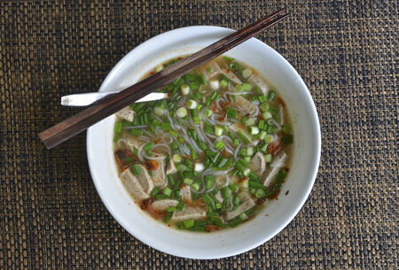 Bowl of Vietnamese rice noodle soup with pork sausage and chopped spring onionの写真素材