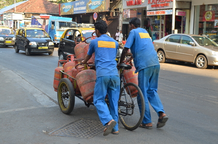 Mumbai, India - December 2013 - Workers delivering LPG gas cylinders on the busy streetのeditorial素材