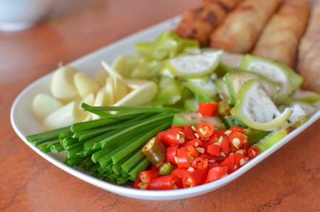 Plate of cut red chili, raw banana, starfruits, chive