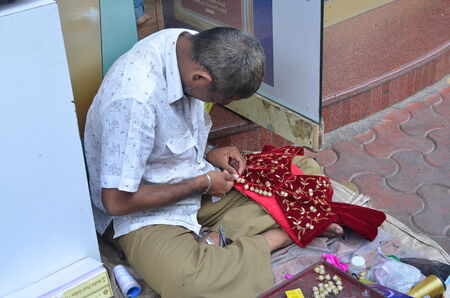 Mumbai, India -January 2014 - Man sewing dress on a footpath in local marketのeditorial素材