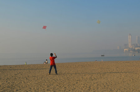 Mumbai, India - January 2014 - young boy flying kite at Chowpatty Beach in the morning のeditorial素材