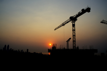 Silhouette crane on top of under construction building at sunset のeditorial素材