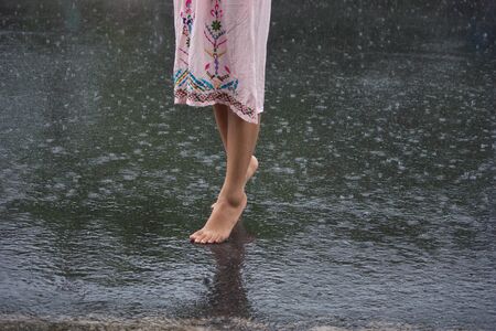 young lady walking on the ground after rainの写真素材