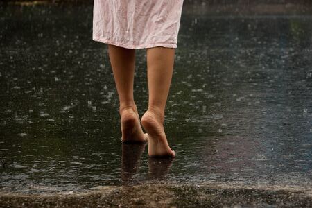 young lady walking on the ground after rainの写真素材