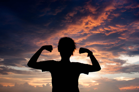 silhouette of young lady show power with armの写真素材