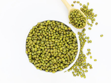 organic mung beans in the white bowl and wood spoon isolated on white background