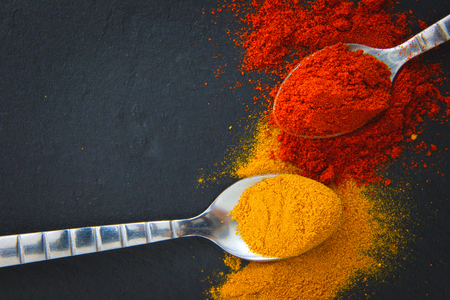 Various Spices (curry and paprika) in spoons on black slate boardの写真素材