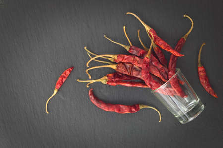 Thai Dried pepper chilies in little glass on black slate plateの写真素材