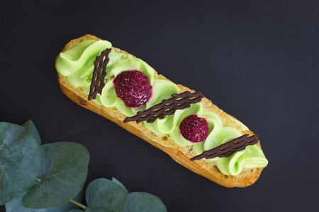Classic French Pistachio Eclair decor by raspberry and chocolate on black slate stone plateの写真素材