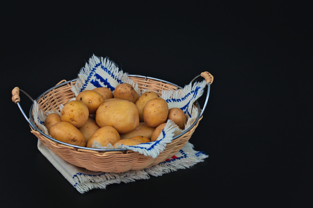 Organic potatoes in the basket on black back groundの写真素材
