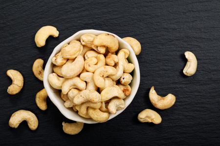 Organic raw Cashew nuts on black slate stone background with copy spaceの写真素材